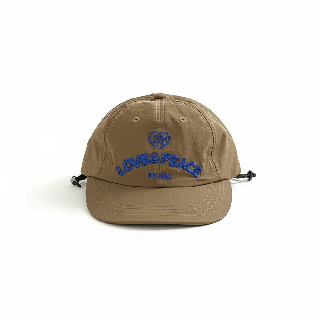 Tan baseball cap with blue 'LOVE & PEACE' embroidery and heart logo, adjustable strap back